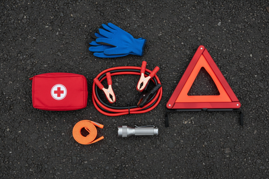 Car emergency kit contents laid out — jumper cables, reflective triangle, first aid kit, flashlight